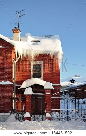 Icicles on the roof of the cottage. Winter.