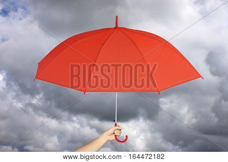 Red umbrella in hand and rain protectionconcept for management business idea on rain cloud background.