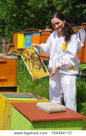 Woman beekeper in white suit with bees