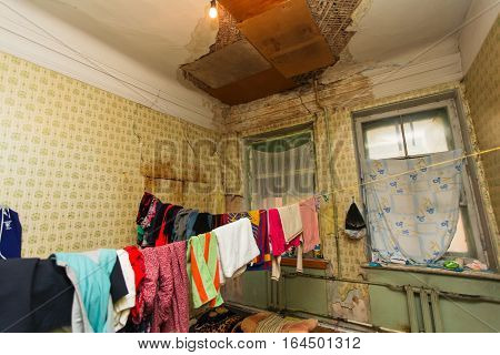 Refugees' clothes is drying of on the rope in the temporary apartment with damaged ceiling
