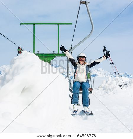 Happy female skier riding a lift. Skiing in sunny weather.
