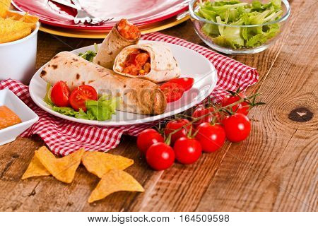 Tortilla wraps with chicken and vegetable on white dish.