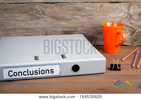 Conclusions. Folder, Coffee Mug, colored pencils on wooden office desk.