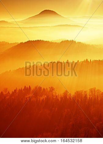 Red filter photo. Red daybreak. Misty daybreak in a beautiful hills. Peaks of hills are sticking out from foggy background the fog is red and orange