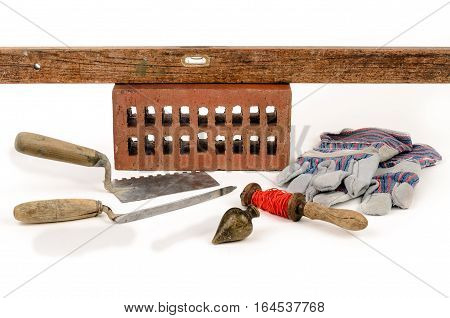 Old construction accessories trowel bricks plummet and level on white background.