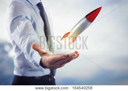 Businessman holding a small rocket. Startup working enterprise concept