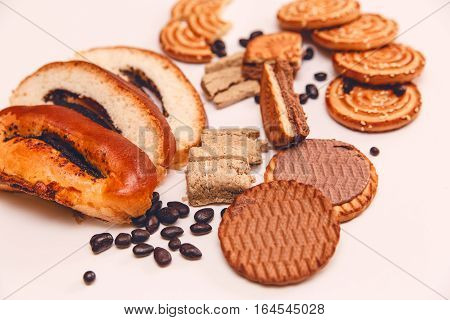 There are Pieces of  Roll with Poppy seed,Cookies,Halavah,Chocolate Peas,Tasty Sweet Food on the White Background