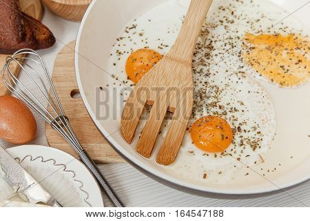 Fried Eggs in the Frying Pan,Breakfast Ingredients.Bread,Butter,Whisk.Kitchen Accessories.Cooking Morning Food.White Table