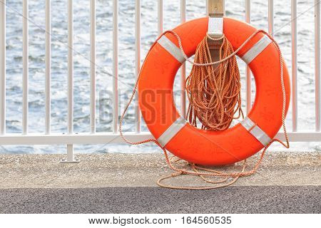 Orange lifebuoy hang on matel fence at the river bank