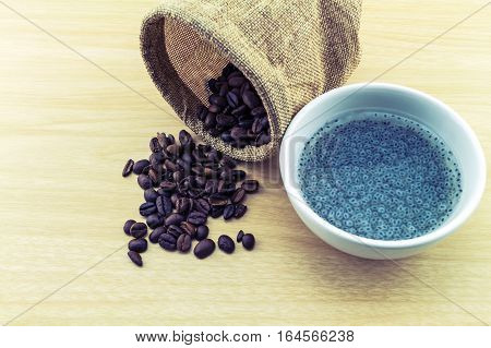 Sweet basil in white cup and coffee beans in sack sisal on wooden background.