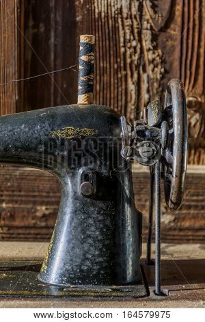 Detali of forgotten black retro sewing machine in abandoned old house. Old classic mechanical sewing machine detail with selective focus.