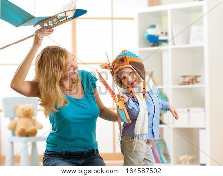 Mother and her child son having a fun playing with toy airplanes at home