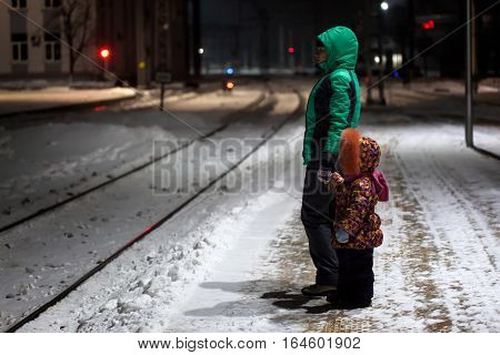 Young woman with child waiting for a train at small railway station at winter night