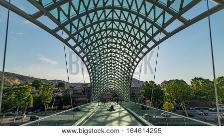Tbilisi, Georgia - August 6, 2015:  Bridge of Peace in Tbilisi, Georgia, bow-shaped pedestrian bridge over the Kura River in Tbilisi, capital of Georgia. One of the most important sites of Tbilisi.