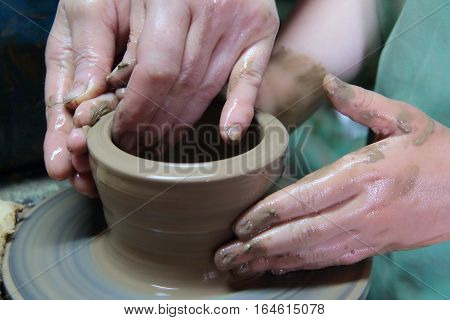 hands of a potter, creating an earthen jar on a pottery wheel