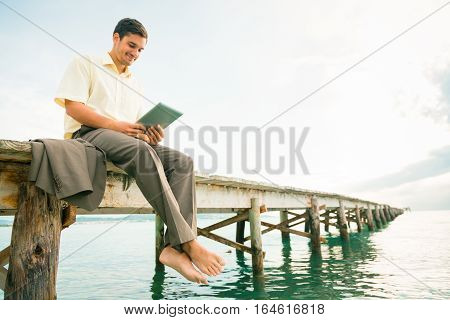 businessman by the sea, working on his digital tablet