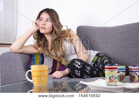 Pensive woman sitting on sofa at home