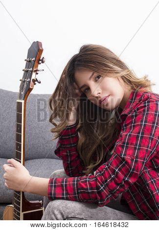 Beautiful girl holding a guitar at home