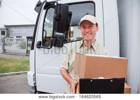 a smiling delivery person is standing next to his truck.
