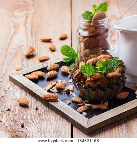 Almond milk in a jug with ingredients for healthy vegetarian vegan breakfast on a rustic wooden table