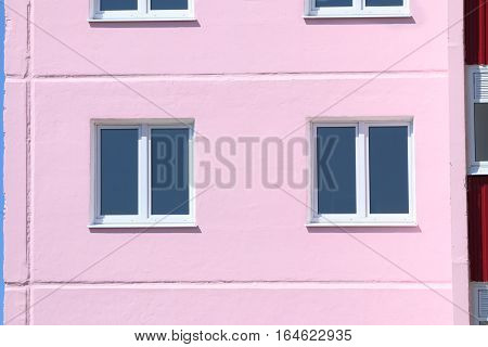 Part of pink residential building with windows with double glazing at sunny day