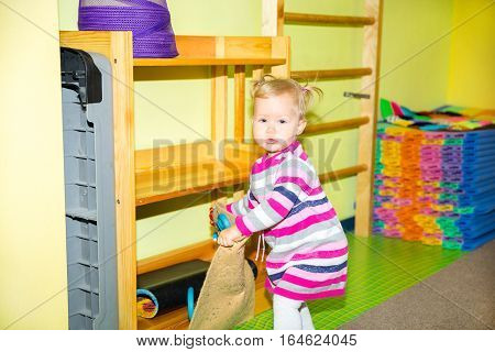 Little child girl playing in kindergarten in Montessori preschool Class. Adorable kid in nursery room.
