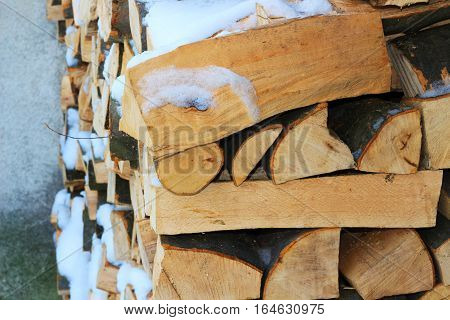 Stacked firewood in winter under the snow. Stock photo