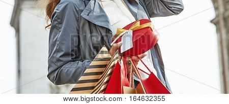 Stylish Christmas in Paris. elegant woman in trench coat with shopping bags and Christmas present near Arc de Triomphe in Paris France looking into the distance
