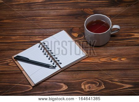 notebook on a table with a mug and a cup of tea