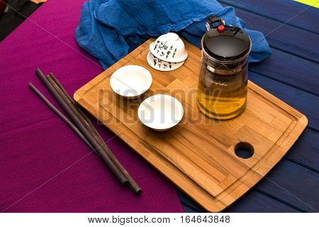 Green herbal tea in glass teapot on the blue wood background with aroma sticks