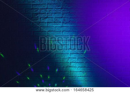 Textured brick wall lit by many colored lights