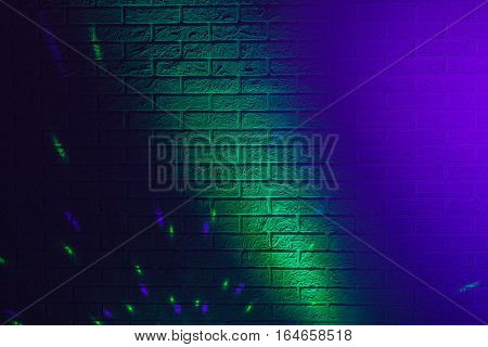 Textured brick wall lit by many colored lights
