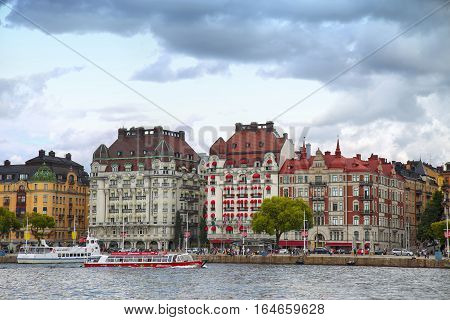 STOCKHOLM SWEDEN - AUGUST 20 2016: Many people walk and visit on Strandvagen street on Ostermalm distric with touristic sightseeing boats in Stockholm Sweden on August 20 2016.