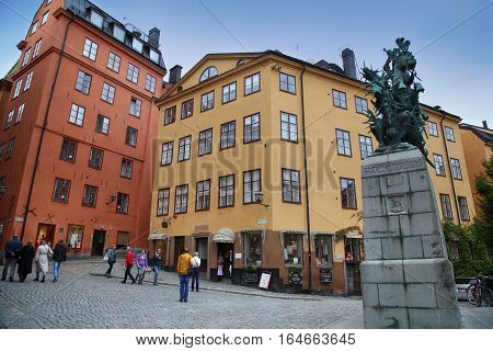 STOCKHOLM SWEDEN - AUGUST 19 2016: Tourists walk and Statue of Sankt Goran & the Dragon located on the Kopmanbrinken street Gamla stan in Stockholm Sweden on August 19 2016.