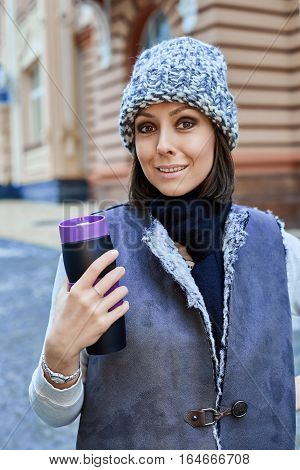 The girl with thermo cup, is walking through the old town