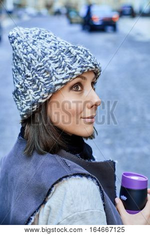 The girl with thermo cup, is walking through the old town