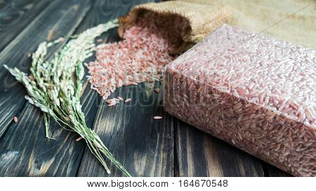 brown rice pack in vacuum plastic bag and paddy on black wood