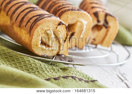 Sweet swiss rolls (roulade) with white cream on green tablecloth