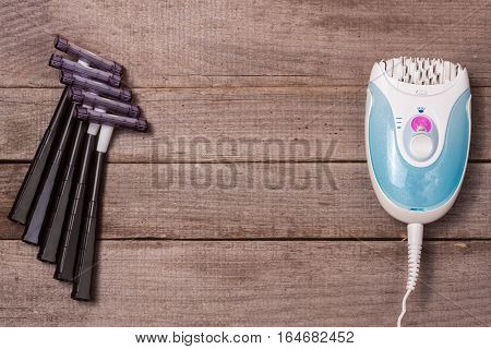 electric epilator with a razor on a light wooden background.