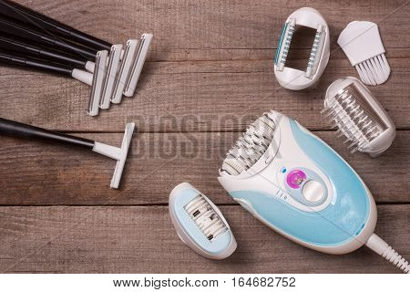 electric epilator with a razor on a light wooden background.