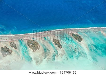 Aerial view of the island with clouds reef and lagoon. Island near Tahiti in the tropical archipelago of French Polynesia inside the Pacific ocean.
