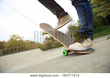 young skateboarder legs riding skateboard at skatepark