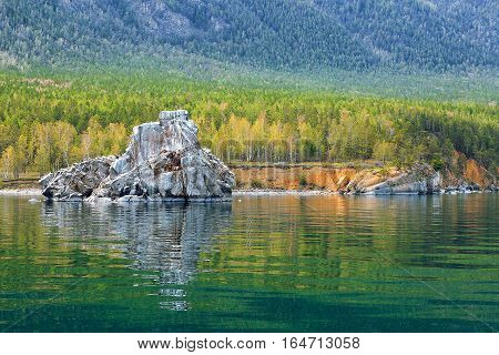 Colorful forest with reflection in water and rock