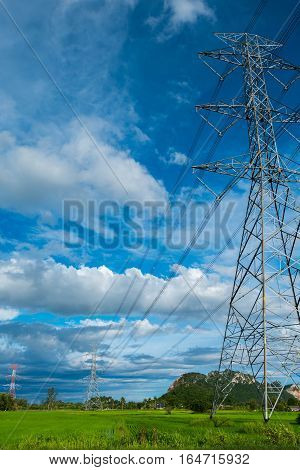 High voltage electricity pylon on the confield have moutain and sky on blackground