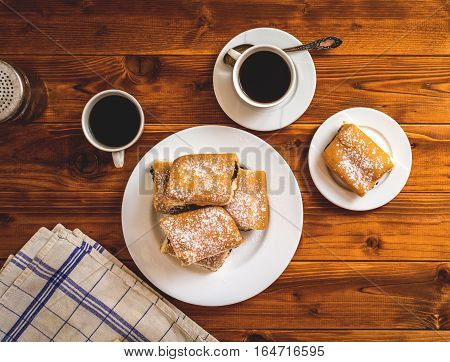 Baked sweet buns with poppy and coffee on wood table