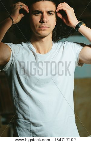 Portrait of a beautiful brutal guy with long hair on a dark background