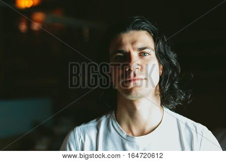 Beautiful long-haired brunette smiling man in a white T-shirt