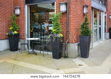 Street caffe for two at the shop window. Flowerbeds marble table and two chairs as a small caffe outside