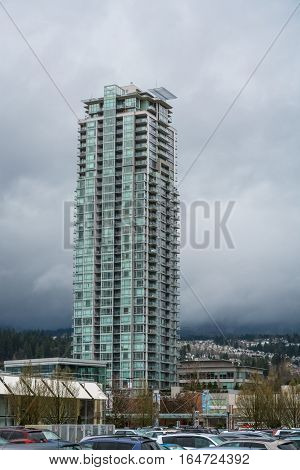 High rise residential building in Vancouver on cloudy sky background. Appartment building with parking lot beside