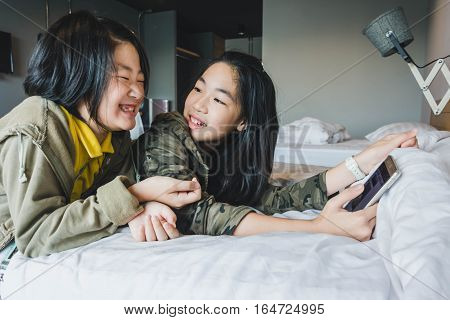 Happy smiling Asian kids on bed playing smart phone technology concept